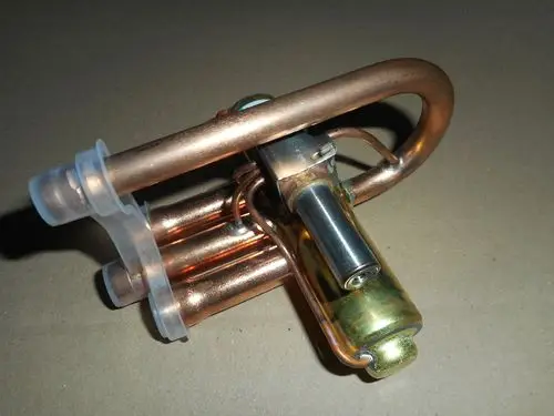 4-Wege-Umschalt-Ventil von Remeha mit Kupferrohren und einem mechanischen Betätigungsmechanismus, geeignet für Heizungsanlagen.